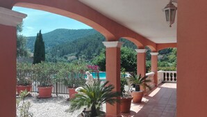 A covered outdoor area with a view of a mountain and a pool.