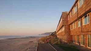 Un edificio costero con una estructura larga y estrecha, un paseo pavimentado y vistas a la playa y al océano.