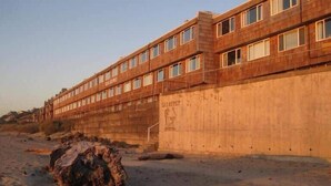 Un edificio grande de varios pisos con techo plano y numerosas ventanas.