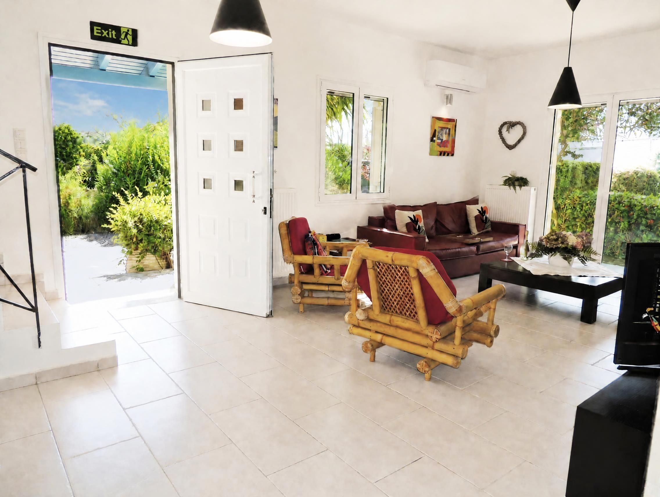 Un salon moderne comprenant un canapé, des fauteuils, un téléviseur et une porte donnant sur un balcon.