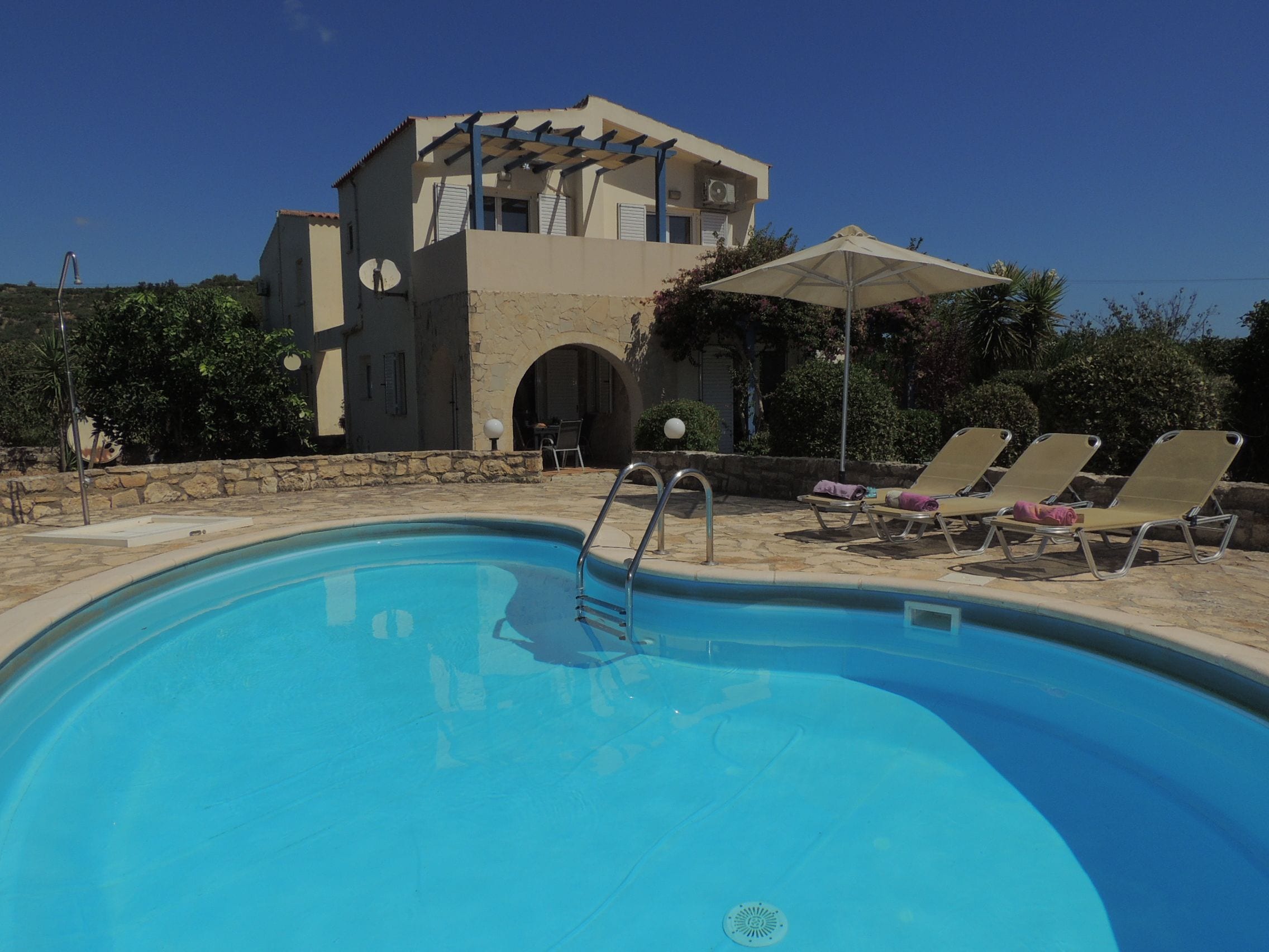 A swimming pool with lounge chairs and a building with a stone facade in the background.
