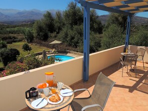 A terrace with a table set for breakfast, overlooking a swimming pool and mountains. - Near Kalives. 2 bedrooms, private pool, Free WIFI, A.C, views and all amenities. (Chania)