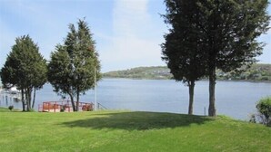 A grassy area with a dock and a red railing by a calm lake.