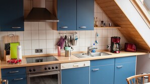 Een keuken met blauwe kastjes, een fornuis en een spoelbak.