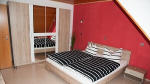 Een slaapkamer met een bed, een kast en een klein nachtkastje.