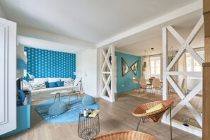 A spacious living area with a blue patterned wall, a white sofa, and a dining area with chairs and a table. - ALFAMA -CASTLE - TERRACE - TAGE VIEW (LISBONNE)
