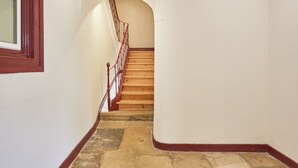 A staircase with wooden steps and a red railing, leading to an upper floor.