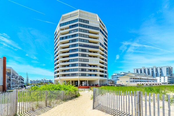 A multi-story hotel with a modern design, featuring balconies on each floor and a central entrance.