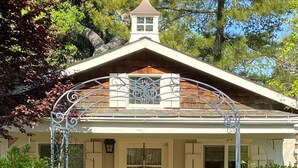 Ein Haus mit überdachter Veranda, einer Haustür und einem kleinen Fenster darüber.