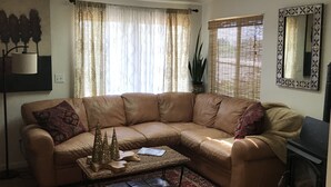 Ein Wohnzimmer mit Ledersofa, Couchtisch, einem gemusterten Teppich, Kamin und einem großen Spiegel an der Wand.