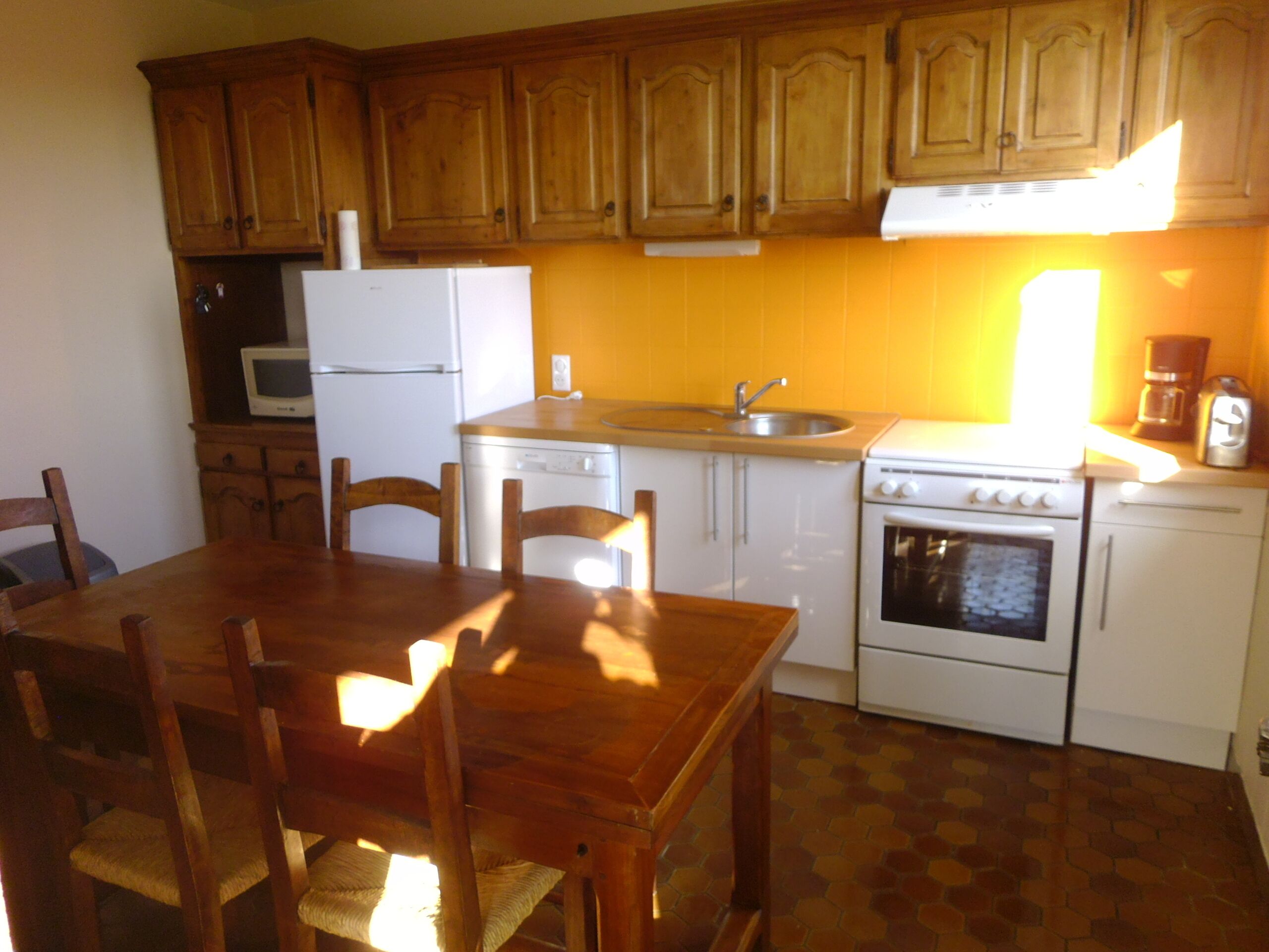 Una cucina con mobili in legno, un frigorifero bianco, una lavastoviglie, un lavello e un piano cottura.