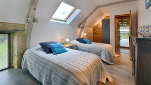 A bedroom with two beds, a skylight, a stone wall, and a wooden door. - La Grange aux Lumières - Heated swimming pool - Nature (Courcy)