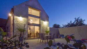 A stone building with a large glass door, a spiral staircase, and outdoor seating. - La Grange aux Lumières - Heated swimming pool - Nature (Courcy)