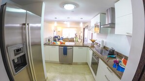 A modern kitchen with stainless steel appliances, a central island, and a view into the living area. - RELAXING OCEAN VIEW CONDO (Oranjestad West)
