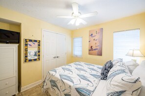 Relax in a cozy space with a comfortable bed, ceiling fan, and wall-mounted TV.