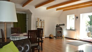 A cozy living room with a fireplace, wooden beams, a dining table, and a sofa. - Holiday in the Elbe Weser triangle on a Resthof near the North Sea (Hipstedt)