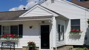 A white single-story house with a front porch, a bench, and flower boxes on the windows.