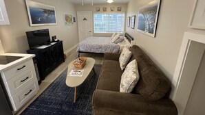 A compact room with a bed, a sofa, a desk, and a television. - Small Private Apartment Within Walking Distance to Beach, Restaurants & Shops (Corona del Mar)