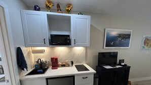 A compact kitchen with white cabinets, a microwave, a coffee maker, and a small refrigerator. - Small Private Apartment Within Walking Distance to Beach, Restaurants & Shops (Corona del Mar)