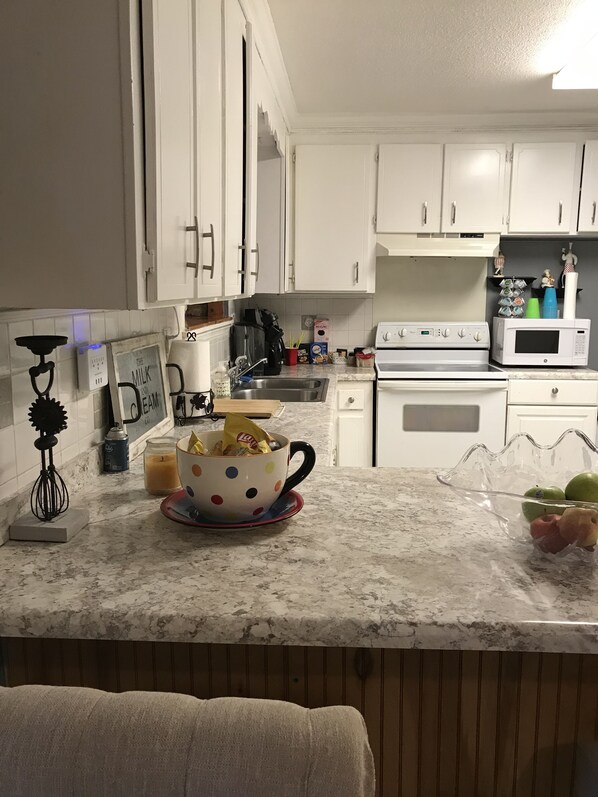 A kitchen with white cabinets, a microwave, a stove, and a coffee maker.