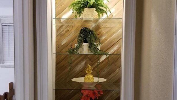 Un couloir avec un mur en bois et une étagère en verre où sont exposés divers objets.