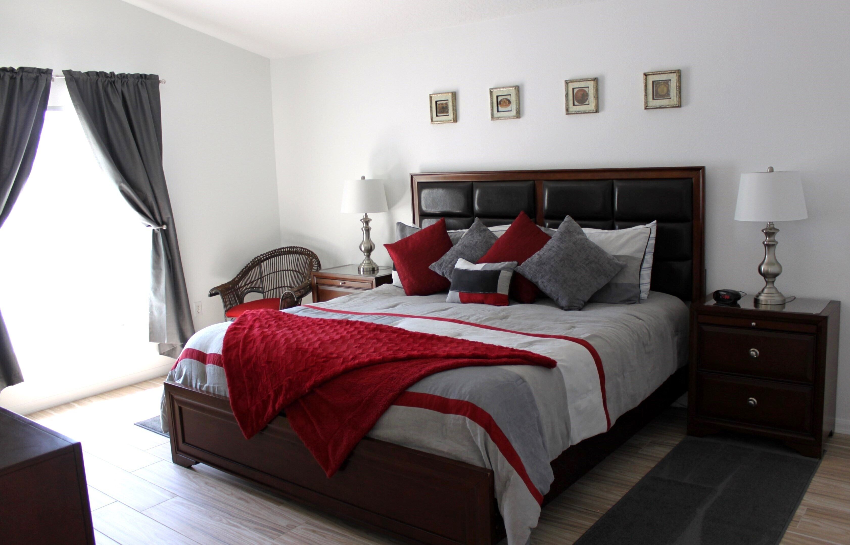 Een keurig ingerichte slaapkamer met een groot bed, nachtkastjes, een stoel en een raam met gordijnen.