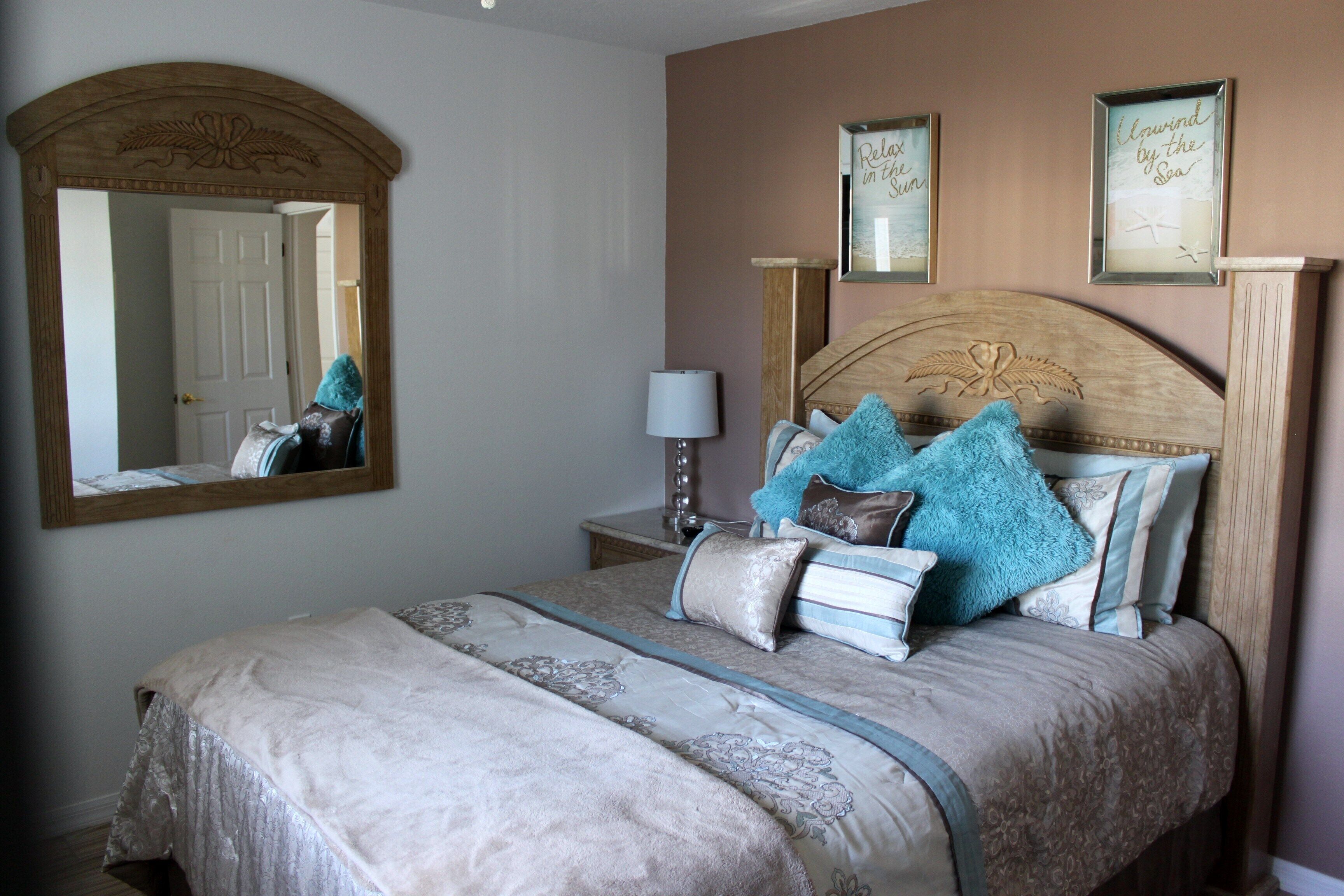 A bedroom with a large bed, a nightstand, a mirror, and framed pictures on the wall.