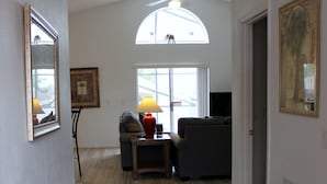 Ein Flur mit Holzboden, Deckenventilator, Fenster mit Ausblick und Tür zu einem anderen Raum.