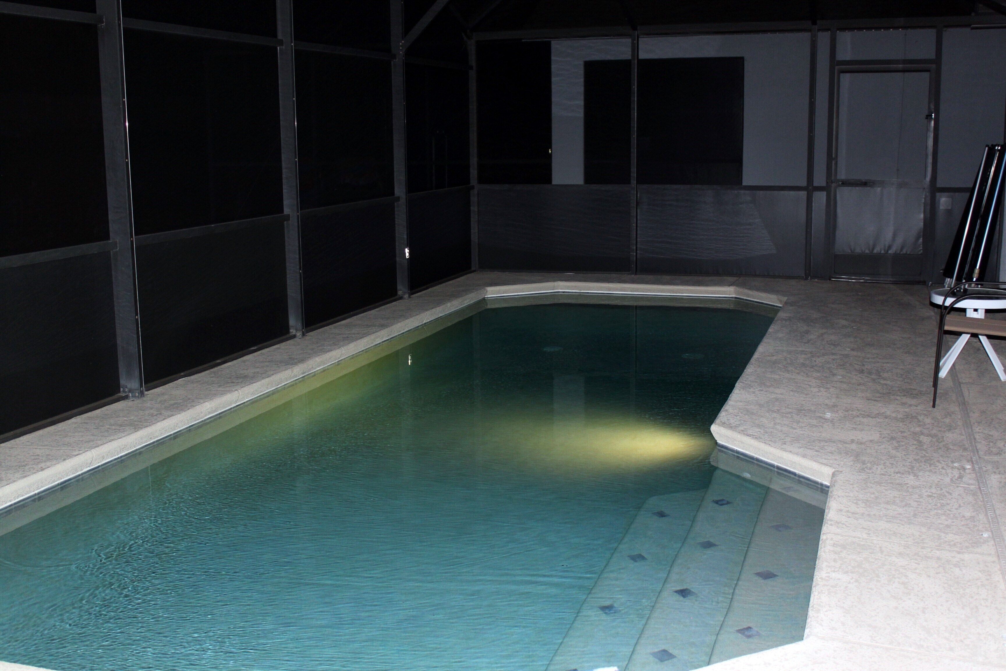 Una piscina interna con bordo piastrellato e struttura in vetro.