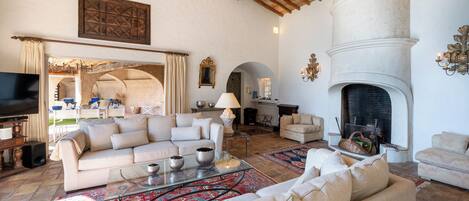 A spacious living room with a fireplace, sofas, and a television.