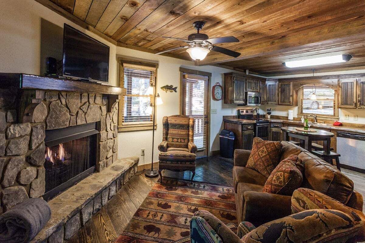 A cozy living room with a stone fireplace, a comfortable sofa, and a television.