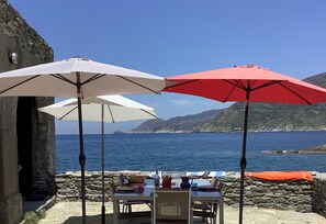 Een terras met tafels en parasols met uitzicht op de kust.