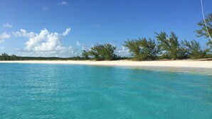 Une mer d’un bleu turquoise limpide, bordée d’une plage de sable et d’une végétation clairsemée.