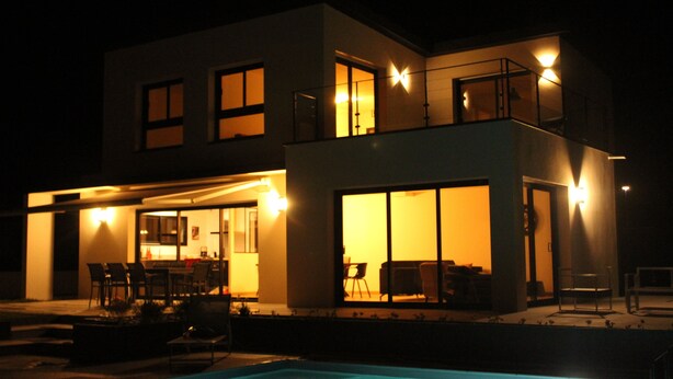 Una casa moderna de dos pisos con una piscina al frente.