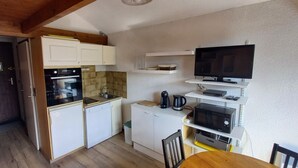 A compact kitchen with white cabinets, a built-in oven, a microwave, and a coffee maker. - studio at the foot of the slopes, view of the mountains, sleeps 5, quiet residence (Les Deux-Alpes)