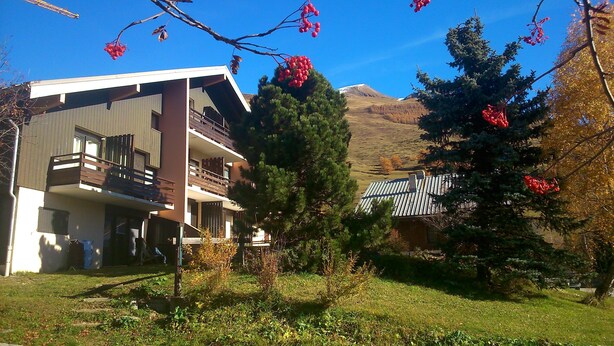 A modern multi-story building with balconies, surrounded by lush greenery and a mountainous backdrop. - studio at the foot of the slopes, view of the mountains, sleeps 5, quiet residence (Les Deux-Alpes)