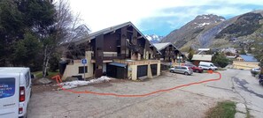 A building with a ski lift, a parking area, and a mountainous backdrop.