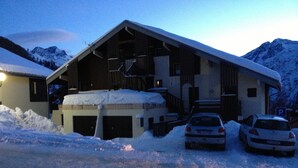 A snow-covered building with a garage and two cars parked in front. - studio at the foot of the slopes, view of the mountains, sleeps 5, quiet residence (Les Deux-Alpes)