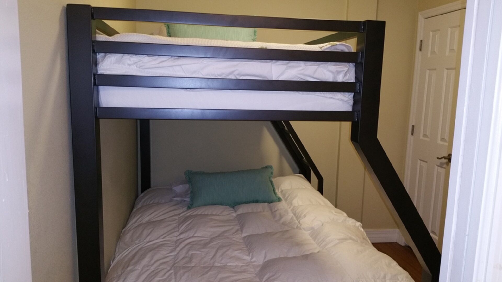 A bunk bed with a green pillow and white bedding.