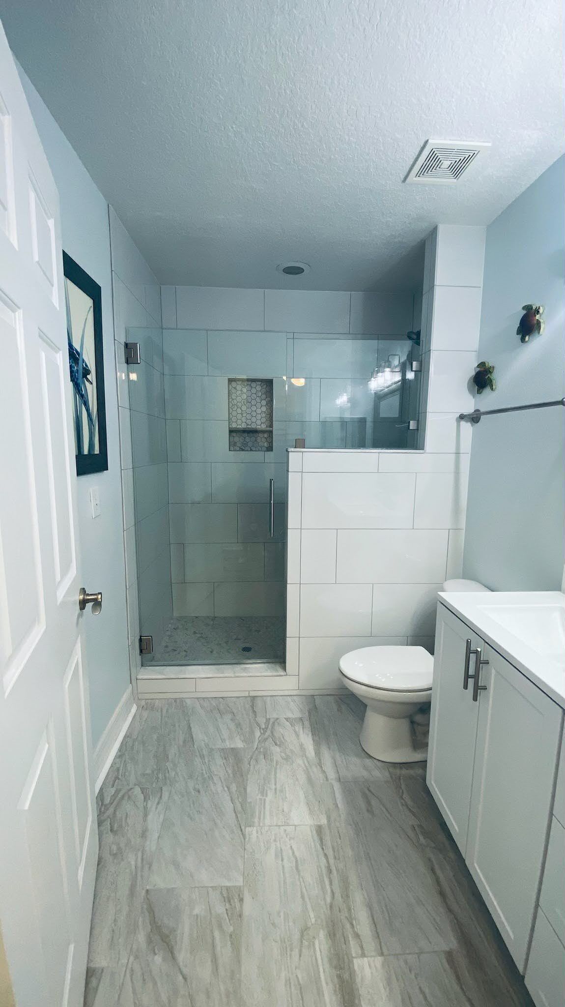 Ein Badezimmer mit Duschkabine, Toilette und Waschtisch mit Schränken.