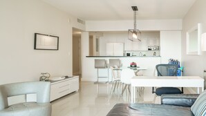 Un salon moderne avec un canapé, une table à manger et une cuisine en arrière-plan.