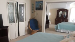 Een slaapkamer met een groot bed, een stoel, een kledingkast en een televisie.