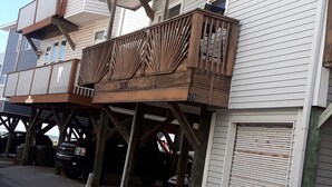Een gebouw met twee verdiepingen, een houten balkon en een garage.