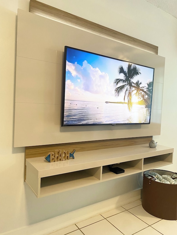 Un televisor de pantalla plana montado en una pared con un estante de madera debajo.