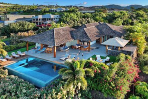 Un resort lussuoso con diverse bungalow sull'acqua, una piscina e una rigogliosa vegetazione tropicale.