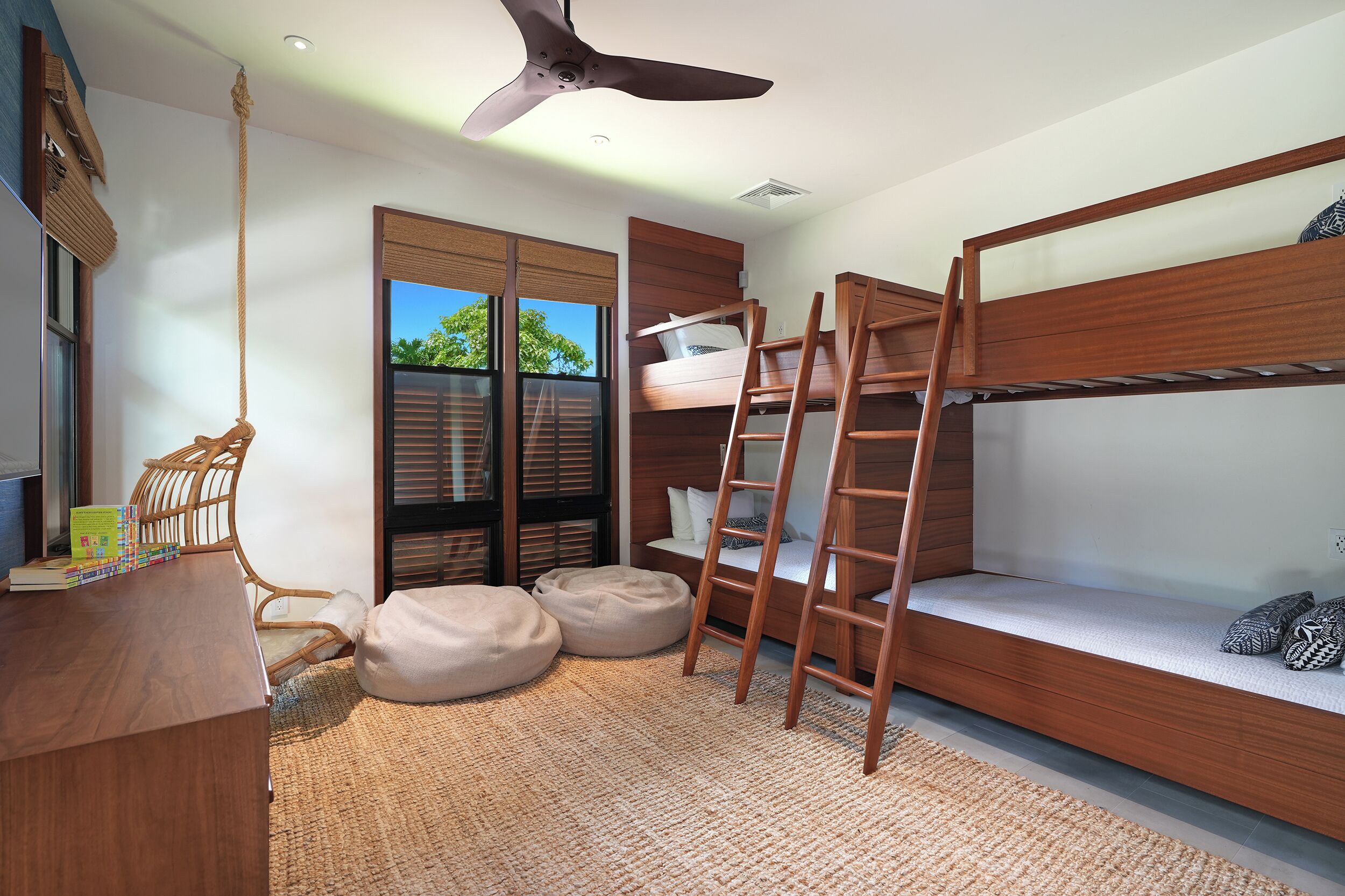 Une petite pièce comprenant un lit superposé, un bureau avec une chaise et un ventilateur de plafond.