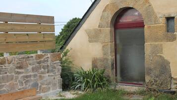 Ein Steinhaus mit roter Tür und Holzzaun.