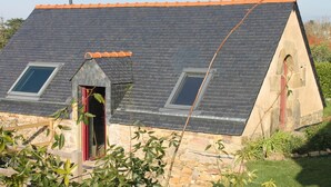 A stone house with a sloped roof, two skylights, and a red door. - Gouelet-Ker "Ouessant" (LOGONNA DAOULAS)