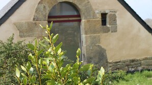 A stone building with a triangular roof and a door with a red stripe. - Gouelet-Ker "Ouessant" (LOGONNA DAOULAS)
