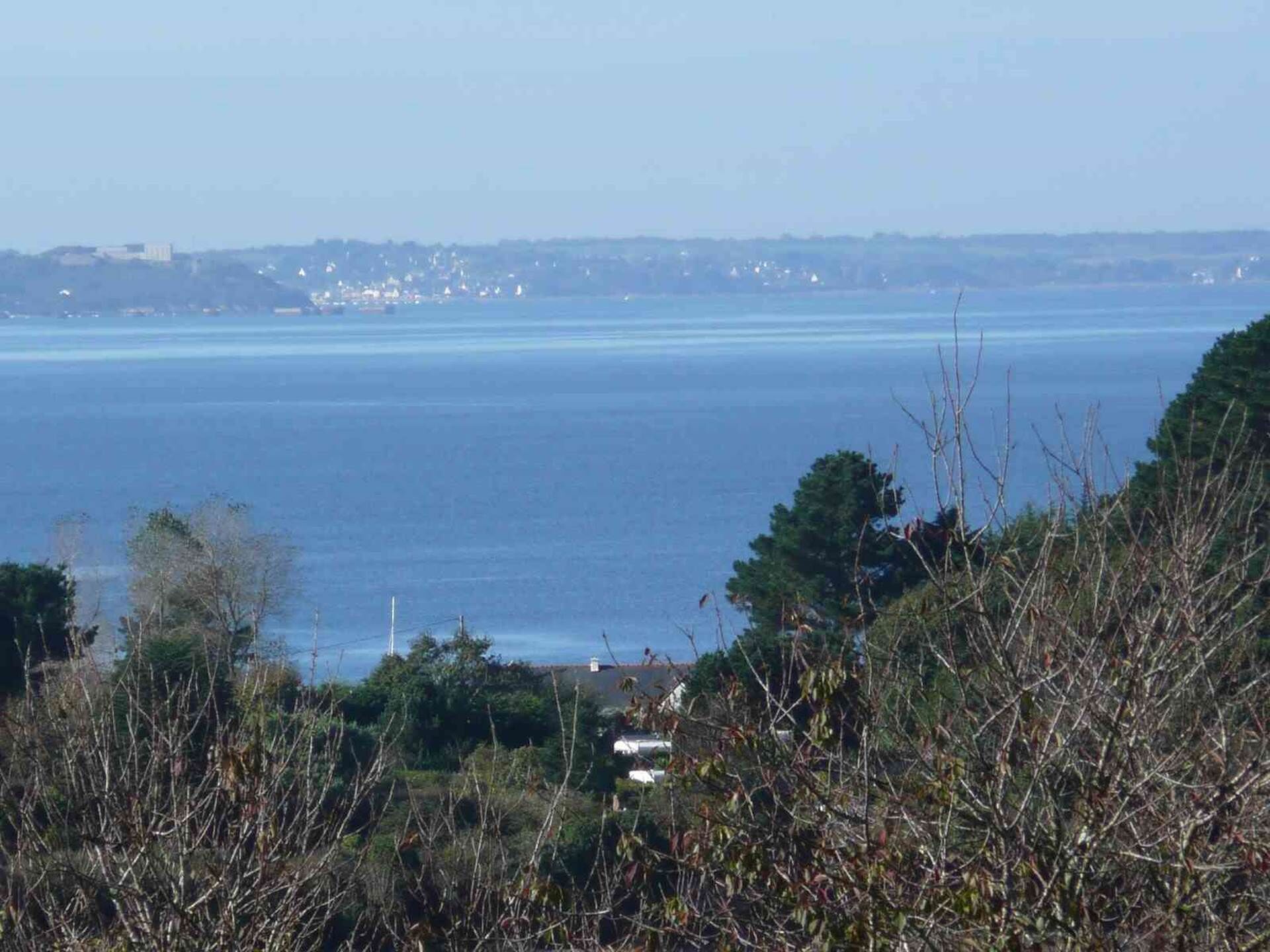 A coastal view with a clear sky, a body of water, and distant buildings.